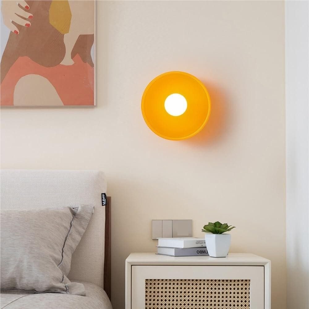 Applique gialla a disco e globo accanto a un letto
