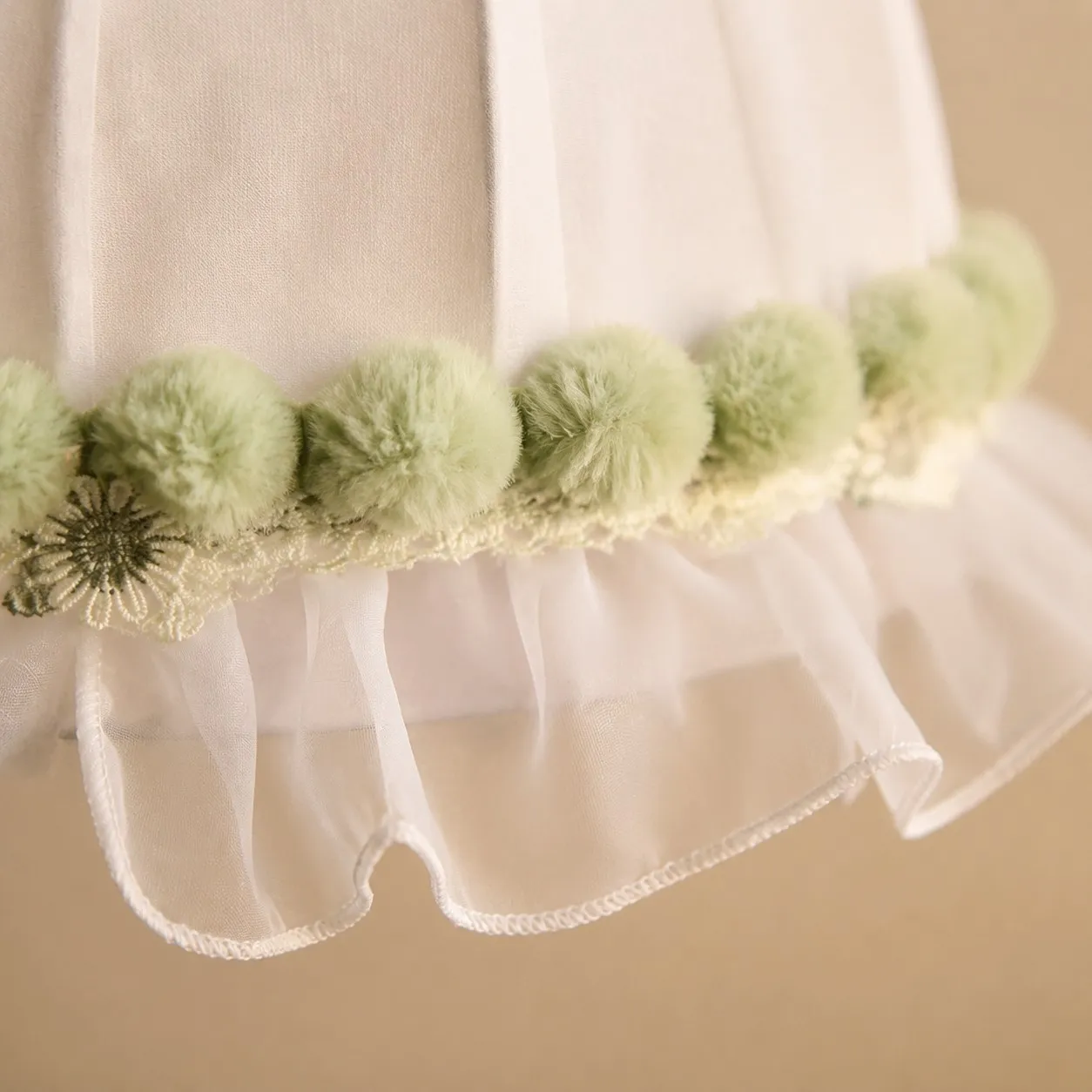 Soft green pom-pom trim and scalloped lace detail