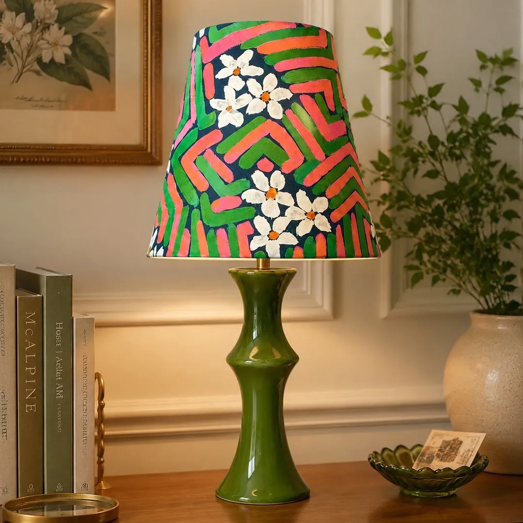 Pink and green table lamp glowing beside framed wall art