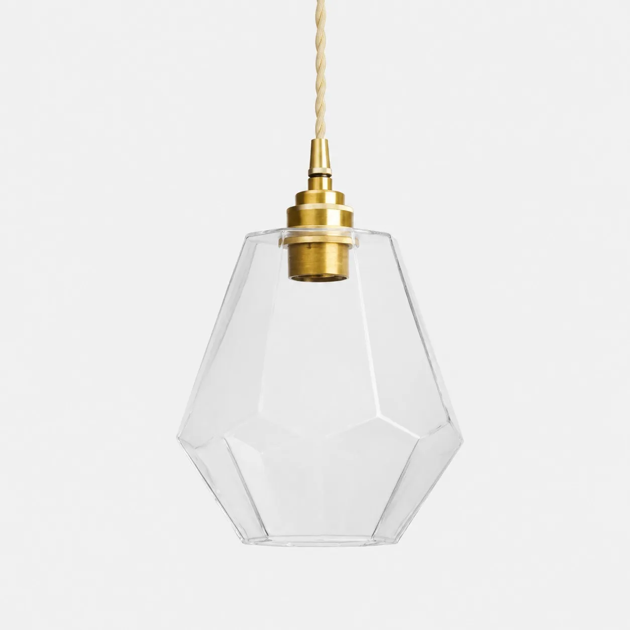 Clear faceted glass pendant light with antique brass holder on white background